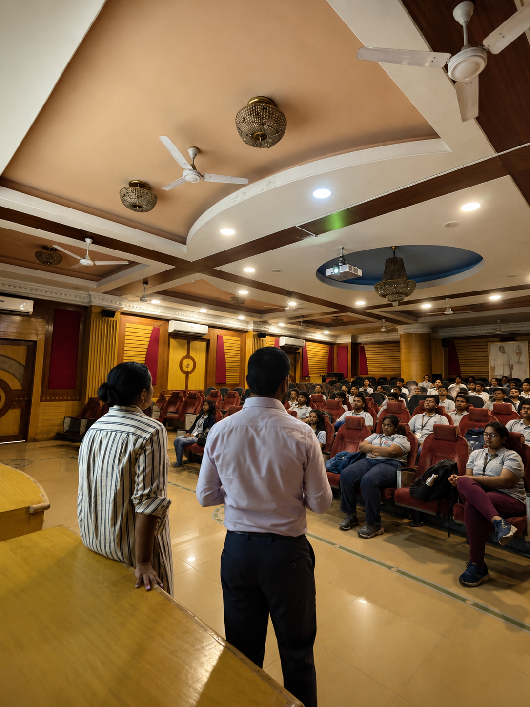 Hriday leading a group session with students seated on the floor of the school hall