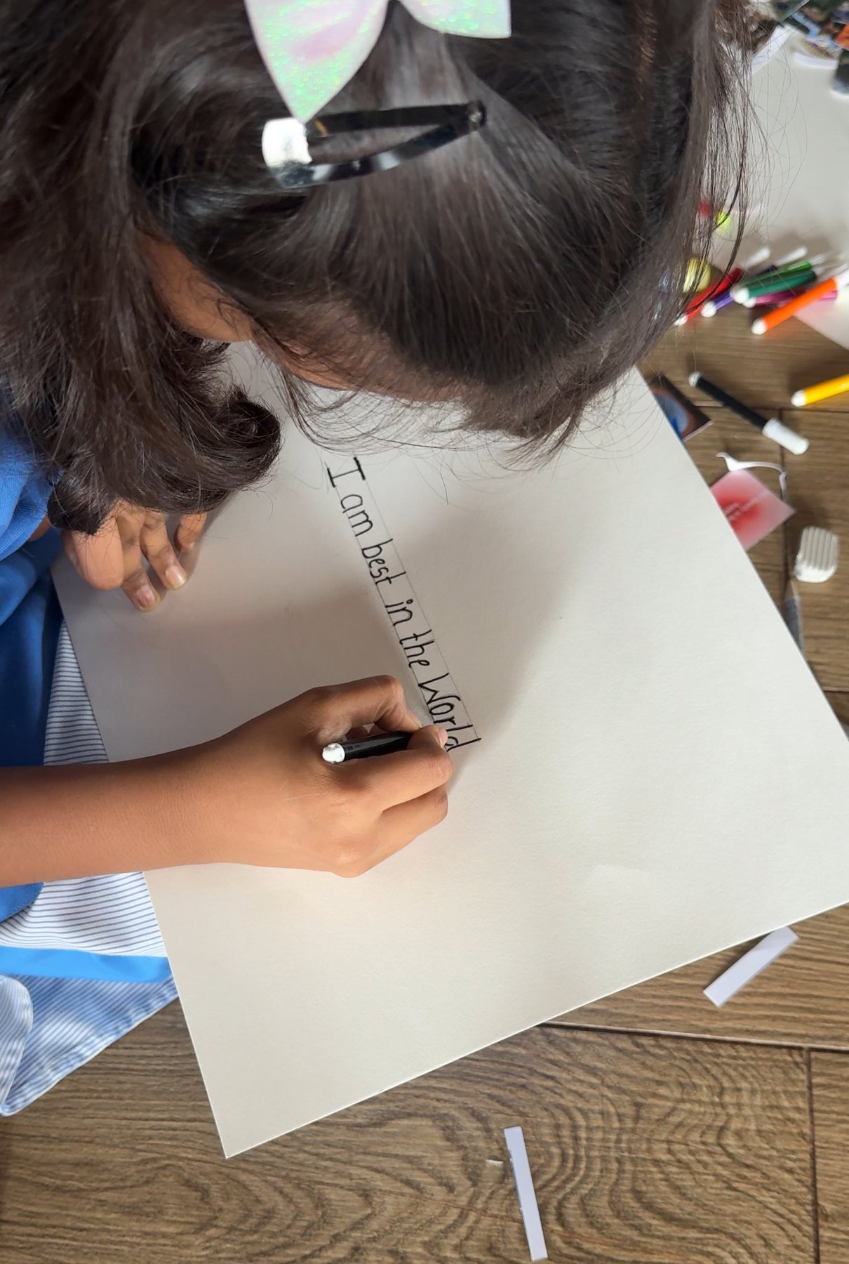 A student writing 'I am best in the world' on her vision board at Dnyan Prakash School