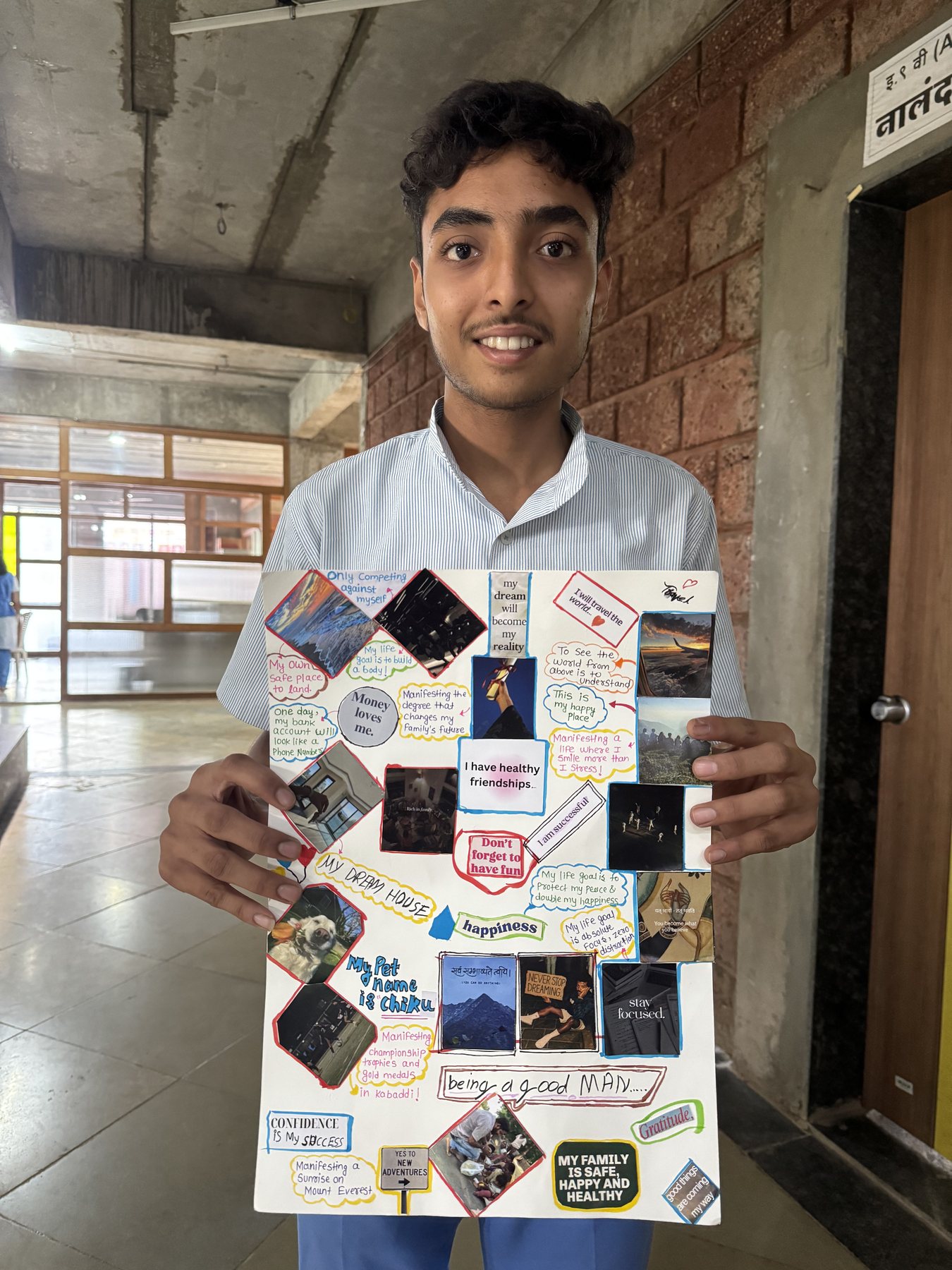 A student proudly holding up his finished vision board at Dnyan Prakash School