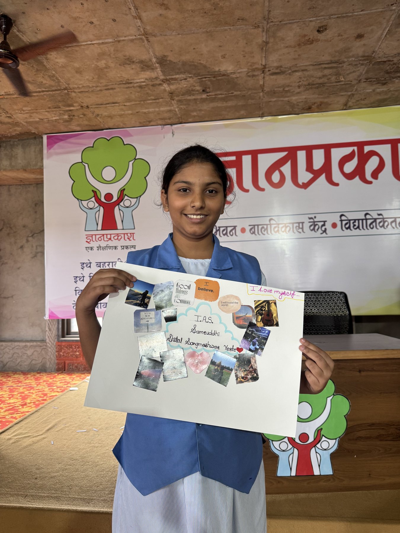 A student proudly holding up her finished vision board at Dnyan Prakash School