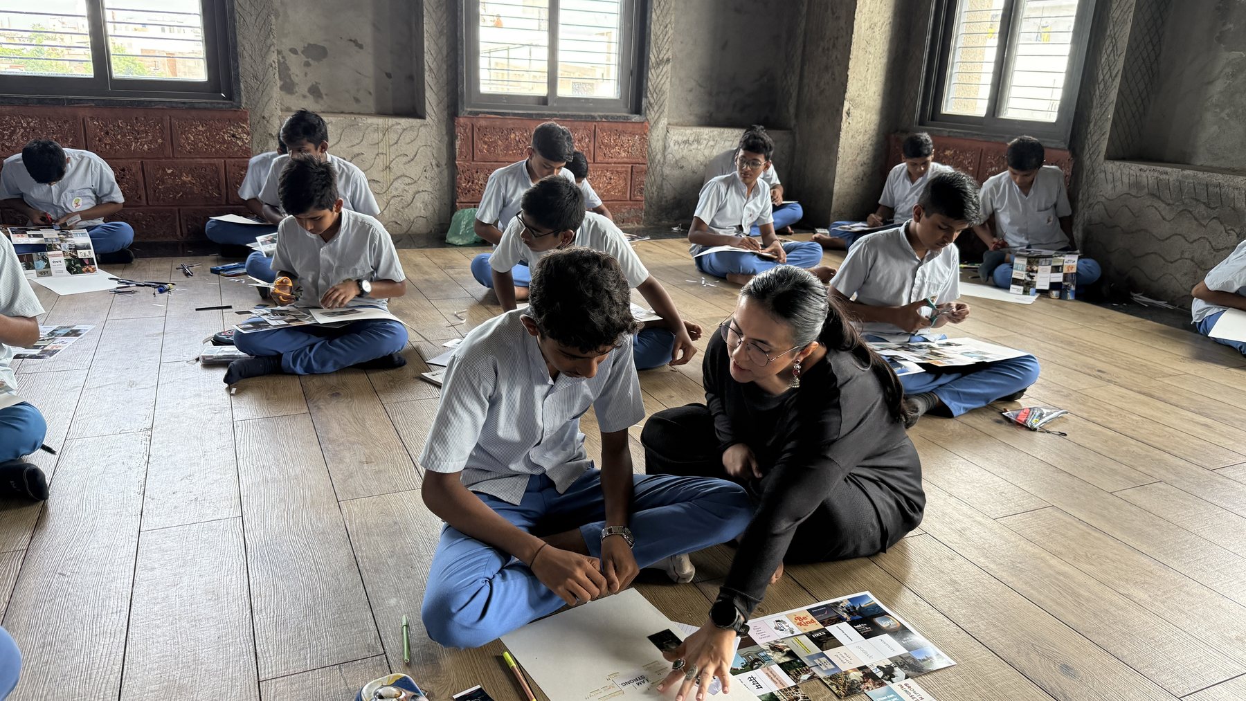 Neha kneeling beside a student, helping him work on his vision board