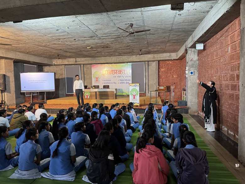 Neha addressing a hall of seated students during a group session